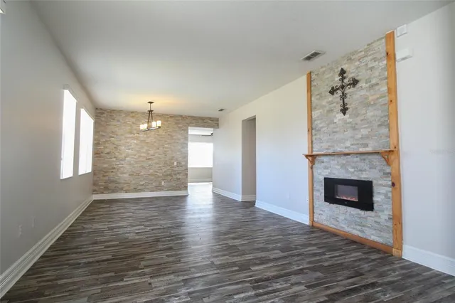 a view of an empty room with wooden floor fireplace and a window