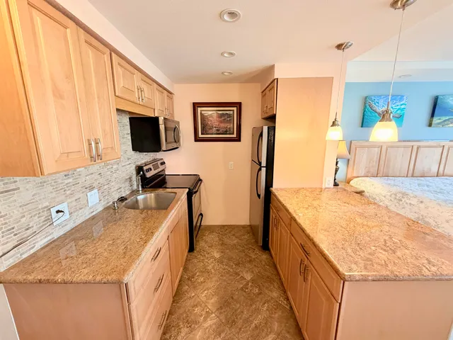 a spacious kitchen with stainless steel appliances granite countertop a sink stove and refrigerator