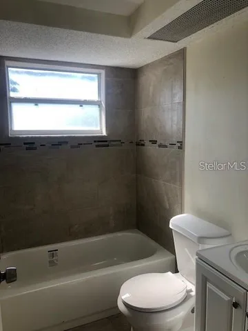 a white toilet and tub sitting next to a window