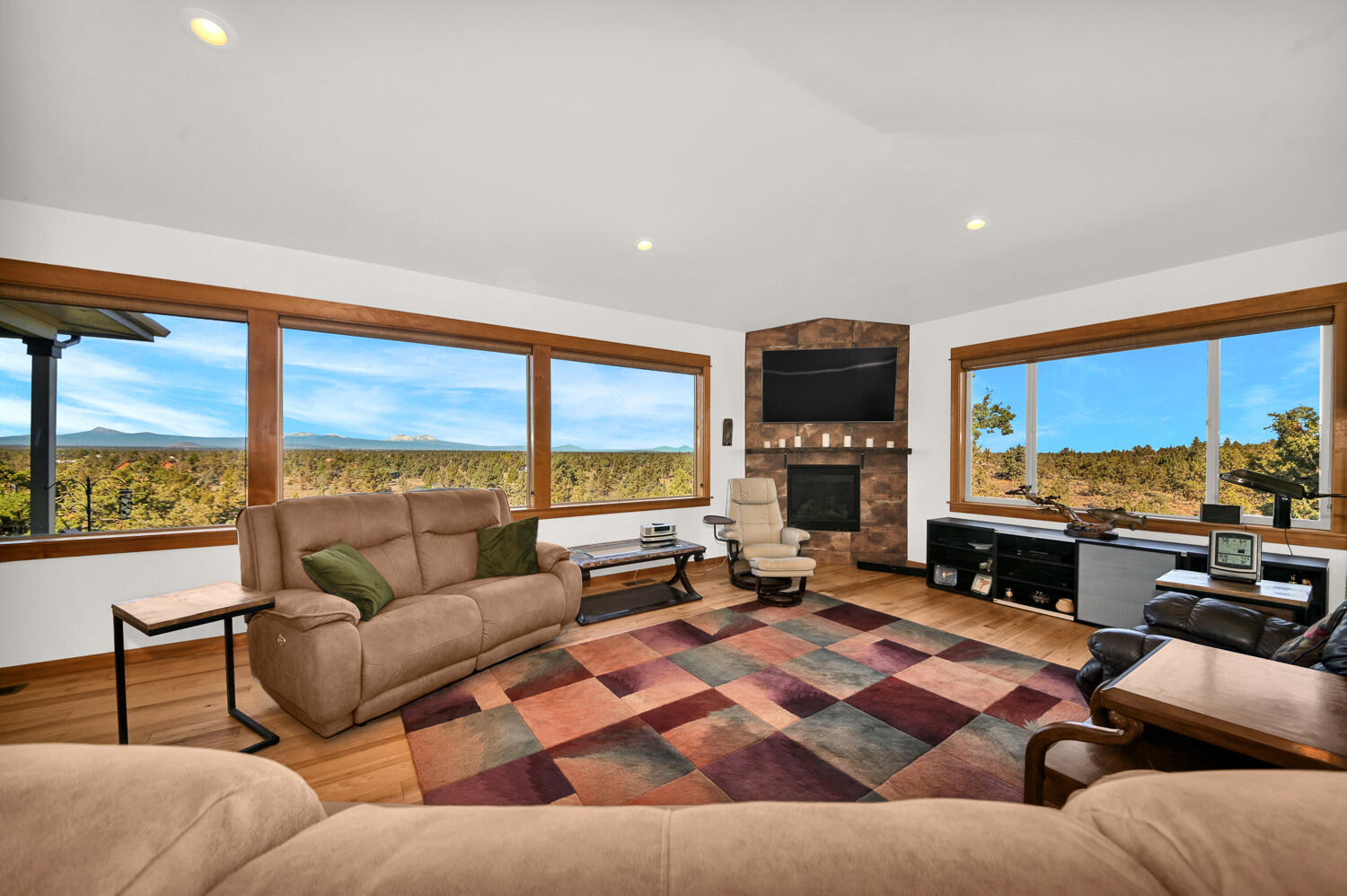 62860 Deschutes Road Bend, OR 97701 - Photo 12 of 34 Living room has a wall of windows to see the mountains, wood floors and a cozy propane fireplace