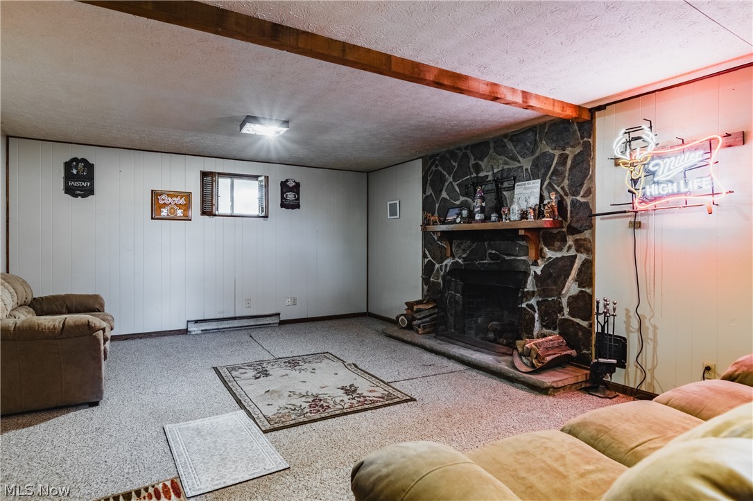 279 Spence Road Belpre, OH 45714 - Photo 25 of 40 Living room featuring a baseboard heating unit, a textured ceiling, a fireplace, beamed ceiling, and carpet flooring