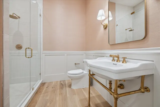 a bathroom with a sink a toilet a mirror and shower