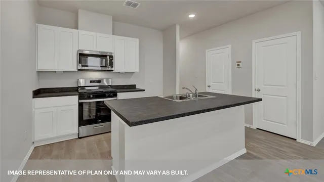 a kitchen with a sink cabinets and wooden floor