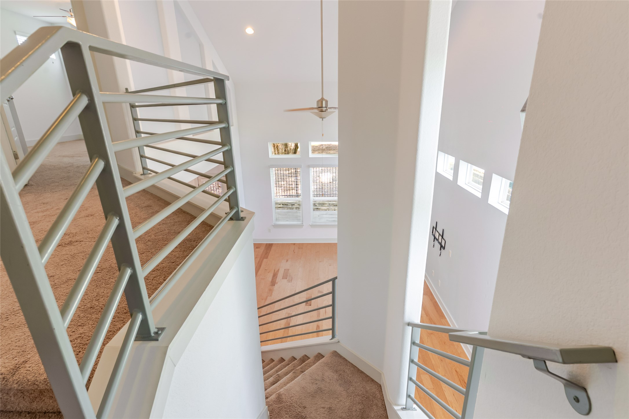 1400 Homespun Road Austin, TX 78745 - Photo 12 of 30 Modern metal railings accent carpeted stairs leading down to a wood-floored living area.