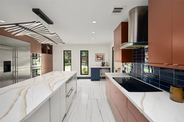 a large kitchen with stainless steel appliances a sink and a refrigerator