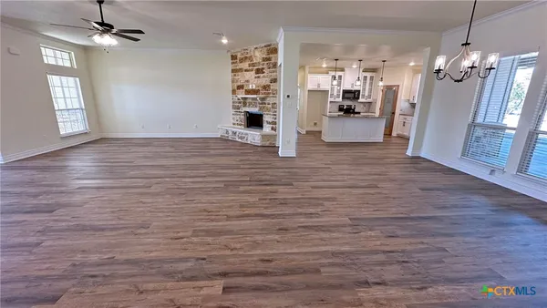 an empty room with wooden floor a fireplace and windows