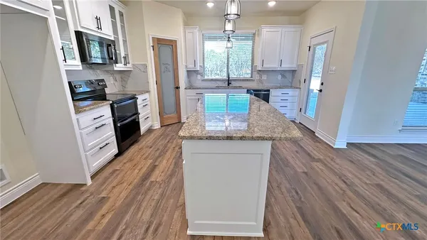 a kitchen with stainless steel appliances granite countertop a refrigerator a stove top oven a sink and dishwasher