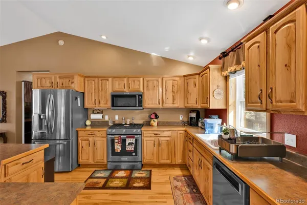 a kitchen with stainless steel appliances a sink dishwasher a refrigerator a stove top oven and a dining table with wooden floor