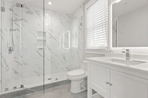 a bathroom with a granite countertop sink a toilet and shower