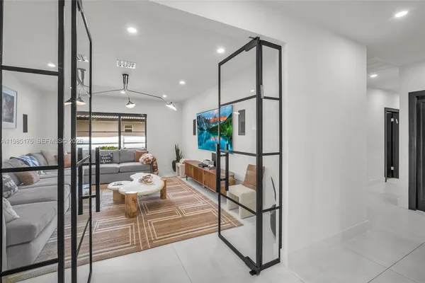 a spacious bedroom with a bed a couch and a flat tv screen on dresser