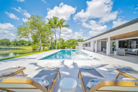 a view of a swimming pool with a yard and palm trees