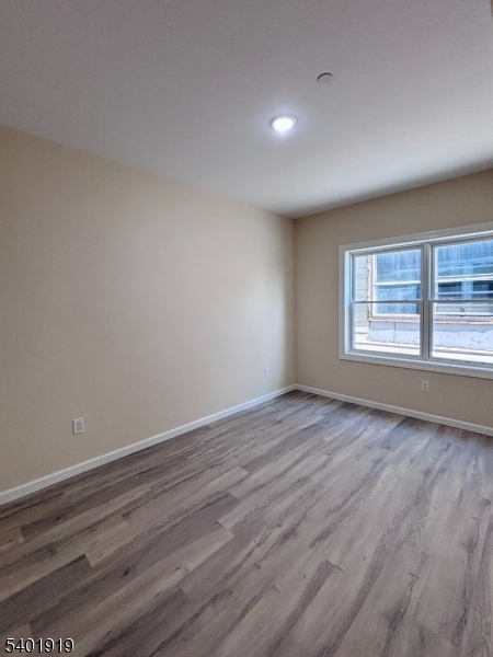 59 Cedar Street, Unit 303 Paterson, NJ 07501 - Photo 2 of 10 a view of an empty room with wooden floor and a window