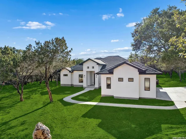 a view of a house with a big yard potted plants and large tree