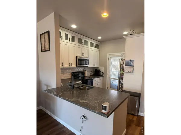 a kitchen with stainless steel appliances granite countertop a sink refrigerator and cabinets