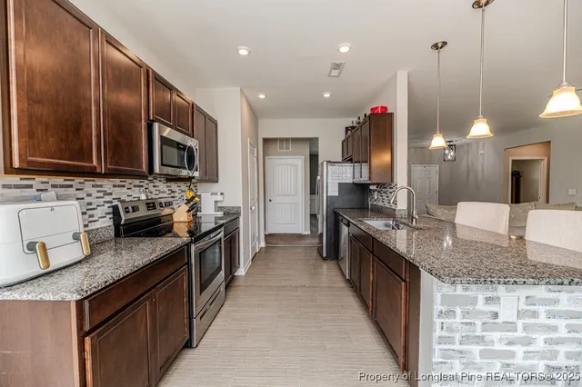 a large kitchen with granite countertop a sink a counter top space a stove and cabinets
