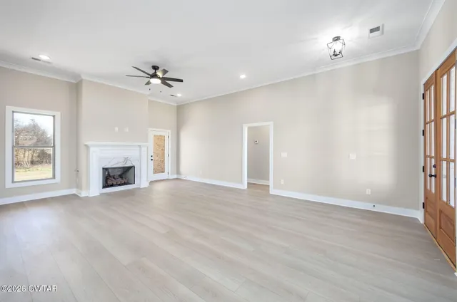 an empty room with windows and fireplace