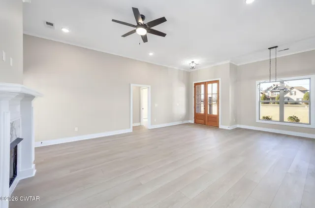 a view of an empty room with a window and wooden floor