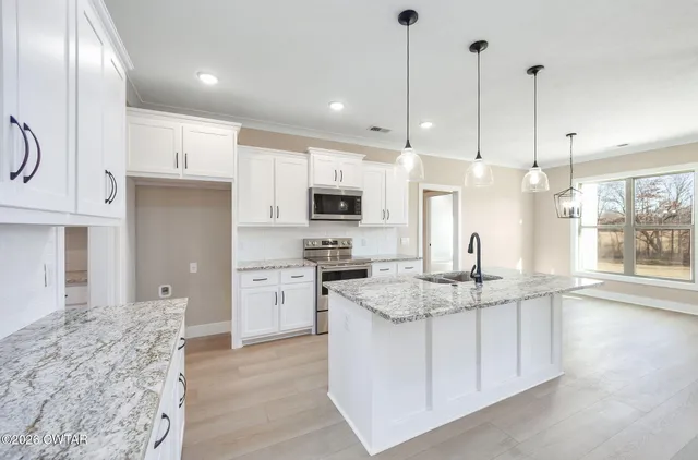 a kitchen with stainless steel appliances granite countertop a sink a stove and a refrigerator