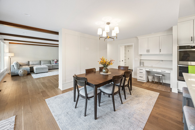 1774 Country Club Drive Logan, UT 84321 - Photo 4 of 28 Open concept dining area featuring wood-finish flooring, a modern chandelier, and an integrated desk area with white cabinetry