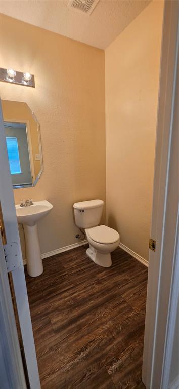2820 Deer Ridge Drive Rockwall, TX 75032 - Photo 16 of 36 Powder room featuring wood-finish flooring, pedestal sink, toilet, wall-mounted vanity lighting, and wall mirror
