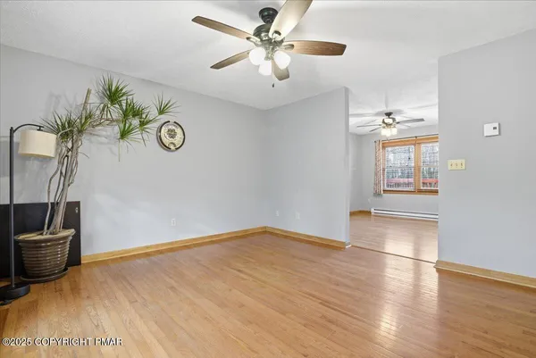 a view of an empty room with window and wooden floor