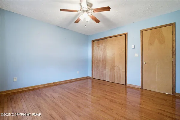 an empty room with wooden floor closet and windows