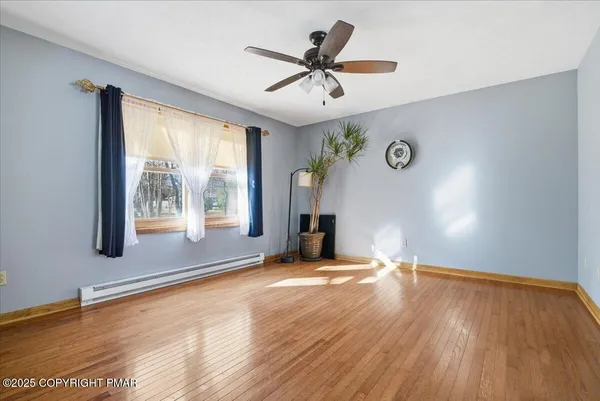 a view of an empty room with a window and wooden floor