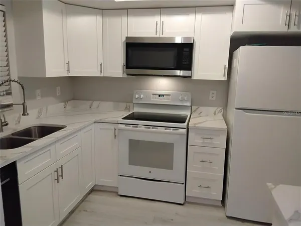 a kitchen with white cabinets and sink