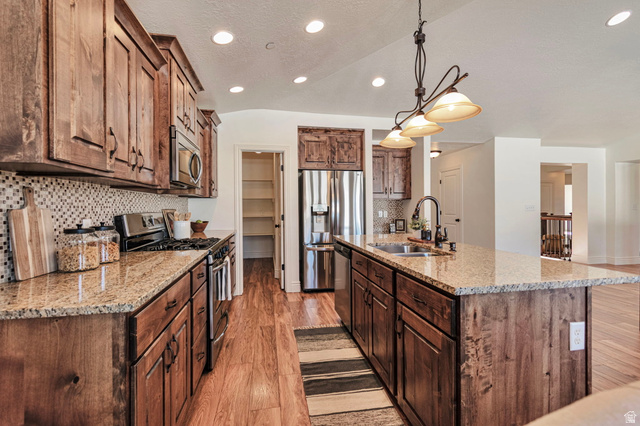 1288 North Horizon View Loop Elk Ridge, UT 84651 - Photo 9 of 40 Kitchen featuring stainless steel appliances, light stone counters, light wood finished floors, an island with sink, and backsplash