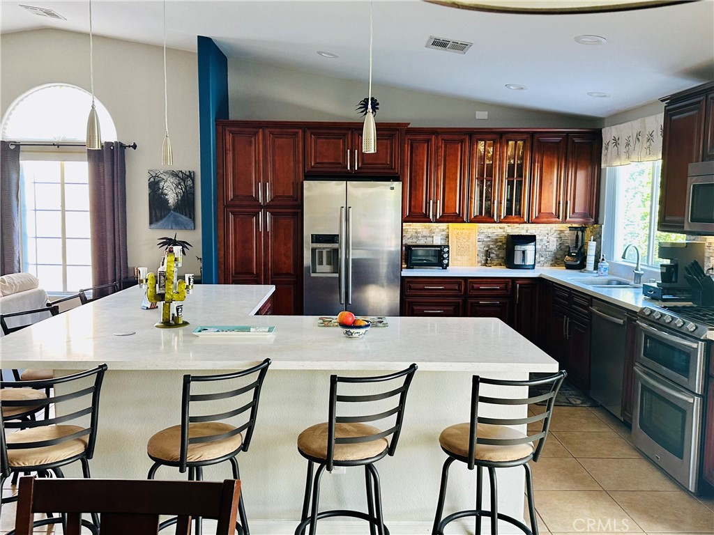 67810 Ontina Road Cathedral City, CA 92234 - Photo 15 of 43 a kitchen with stainless steel appliances kitchen island granite countertop a dining table and chairs
