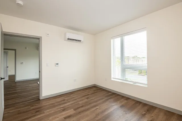 a view of an empty room with wooden floor and a window