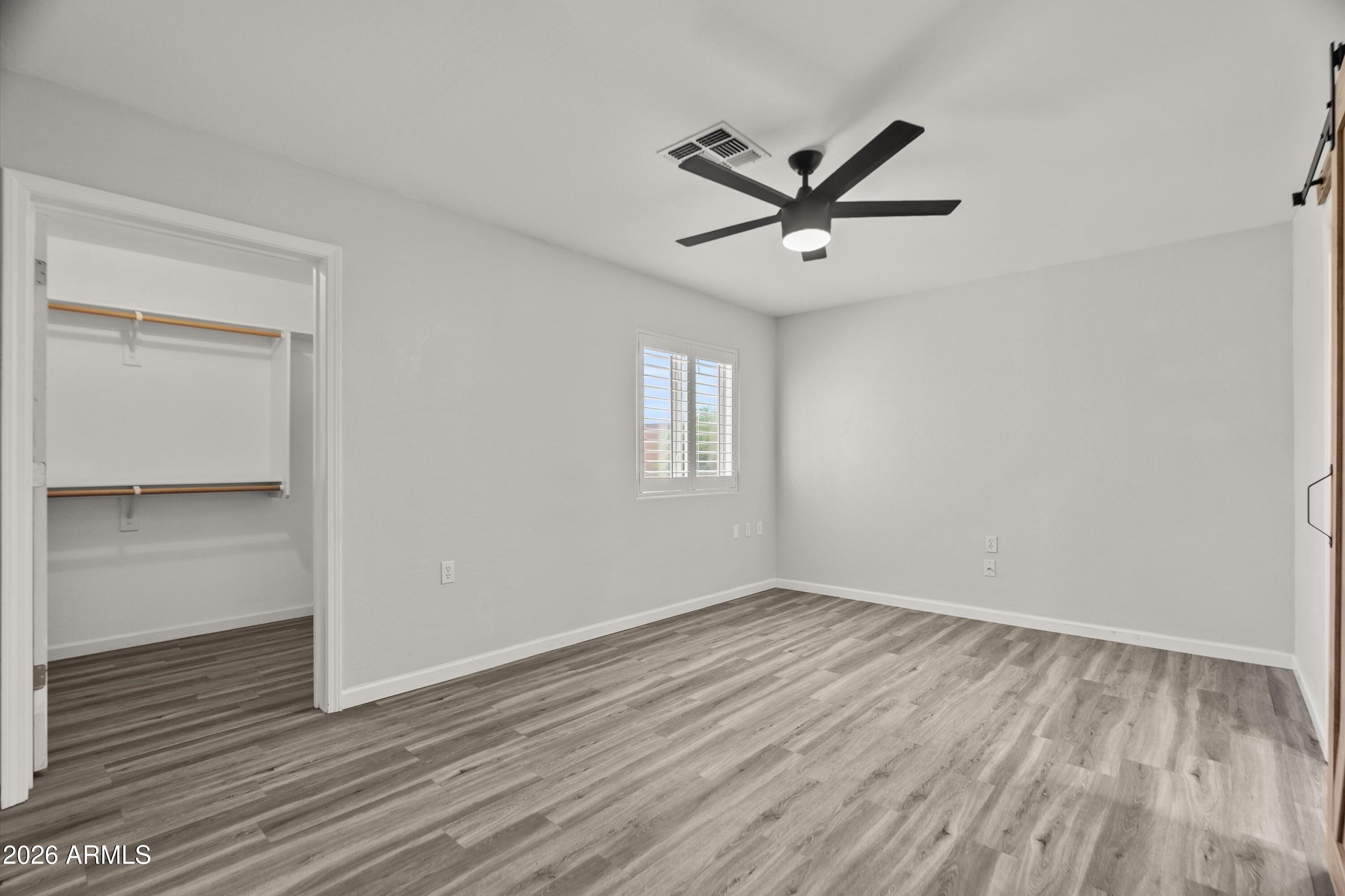 15649 North 29th Place Phoenix, AZ 85032 - Photo 19 of 35 an empty room with wooden floor a ceiling fan and windows