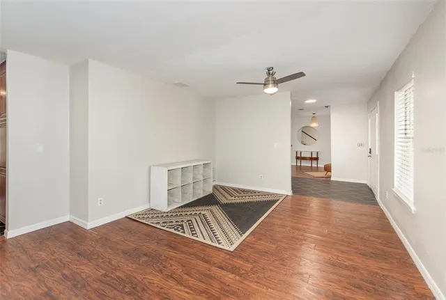 an empty room with wooden floor ceiling fan and window