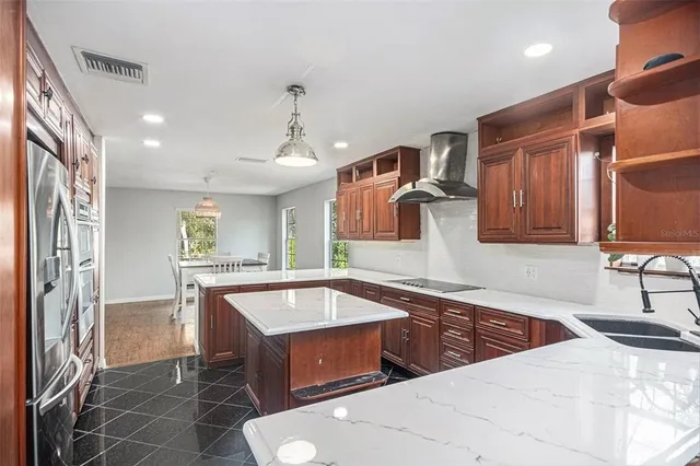 a kitchen with stainless steel appliances granite countertop a sink and a stove top oven with wooden floor