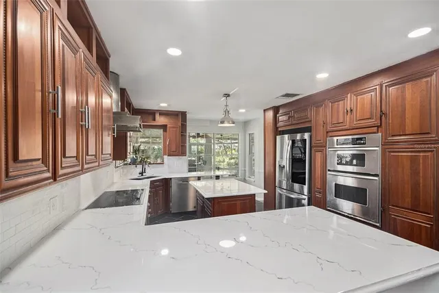 a large kitchen with kitchen island a large window a refrigerator and stainless steel appliances