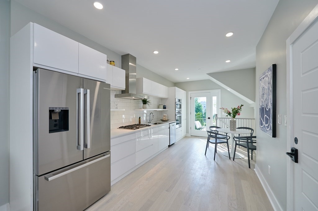 96 Cottage Street, Unit PARLOR Boston, MA 02128 - Photo 3 of 15 a kitchen with a refrigerator a table and chairs