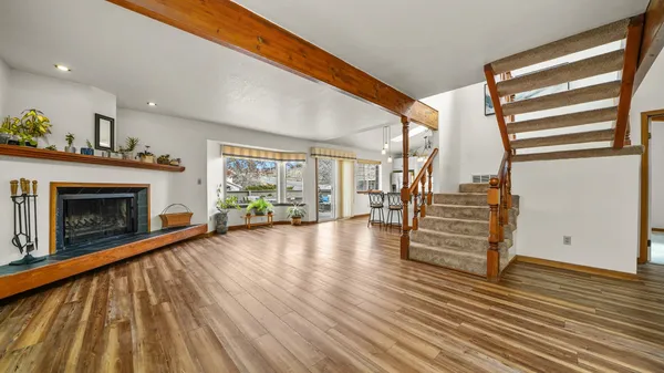 a view of an empty room with wooden floor fire place and windows
