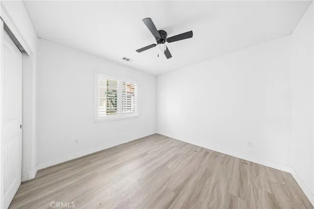 an empty room with wooden floor ceiling fan and windows