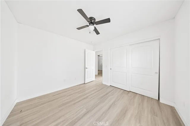 a view of empty room with wooden floor and ceiling fan