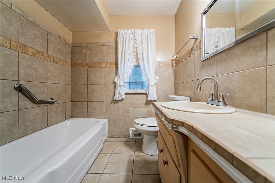 20620 Donnybrook Road Maple Heights, OH 44137 - Photo 16 of 32 Full bath with light tile patterned floors, tile walls, vanity, and bathing tub / shower combination