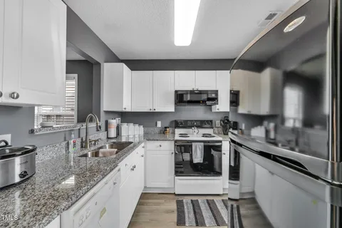a kitchen with stainless steel appliances granite countertop a sink stove microwave and refrigerator