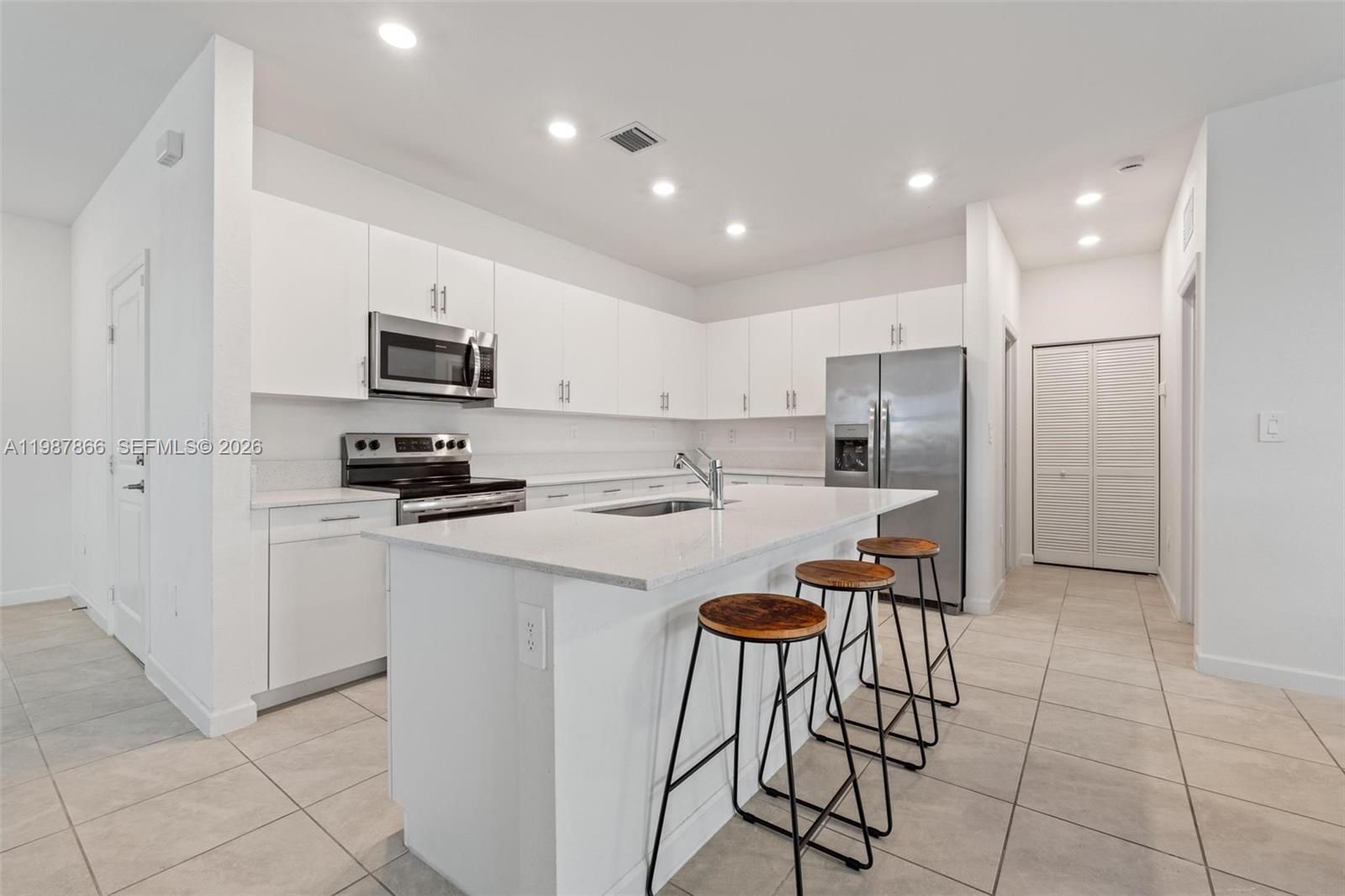 11903 Southwest 241st Street, Unit 11903 Homestead, FL 33032 - Photo 10 of 57 a kitchen with stainless steel appliances a refrigerator a stove a sink a dining table and chairs