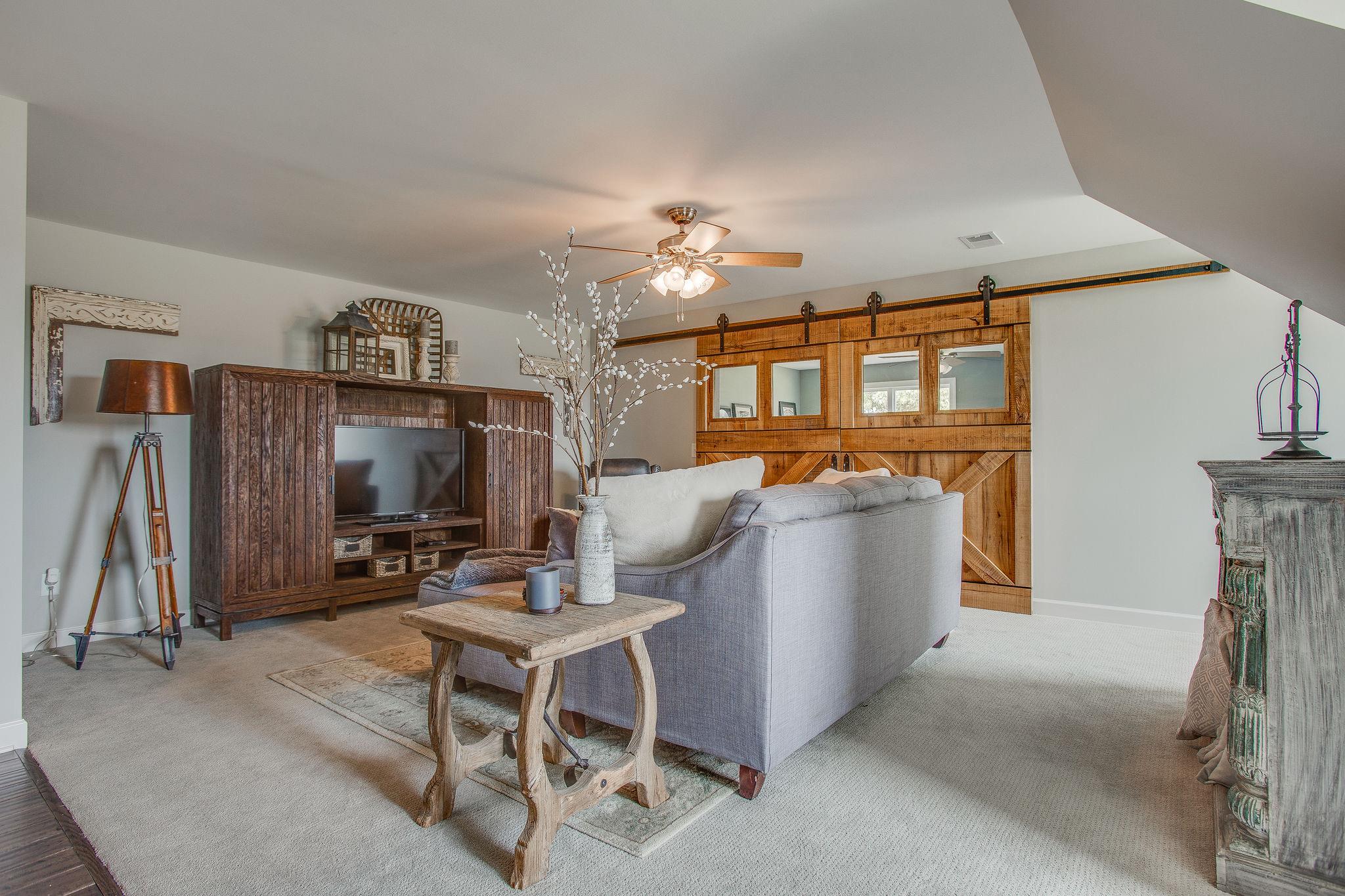 7901 Pinewood Road Fairview, TN 37062 - Photo 20 of 29 a living room with furniture a flat screen tv and a wall painting