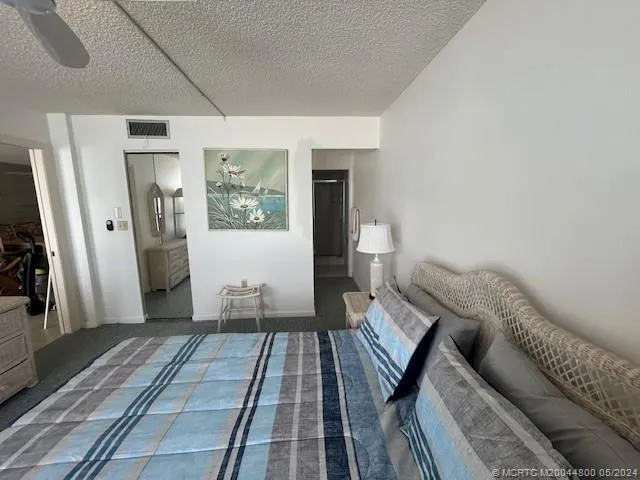 a bedroom with a bed a table and large windows