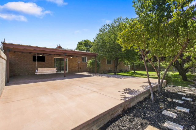 358 West 1200th Street North Mapleton, UT 84664 - Photo 27 of 30 Expansive concrete patio with a covered outdoor area, brick exterior, lush green lawn, and fruit trees.