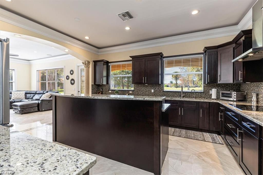 2135 Par Drive Naples, FL 34120 - Photo 5 of 49 a kitchen with stainless steel appliances kitchen island granite countertop a refrigerator a sink dishwasher a stove and black cabinets with wooden floor