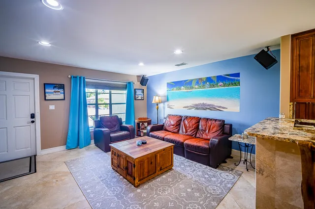 a living room with furniture a flat screen tv and a refrigerator