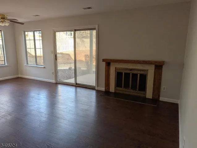 an empty room with wooden floor fireplace and windows