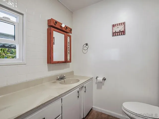 a bathroom with a granite countertop sink mirror vanity and toilet