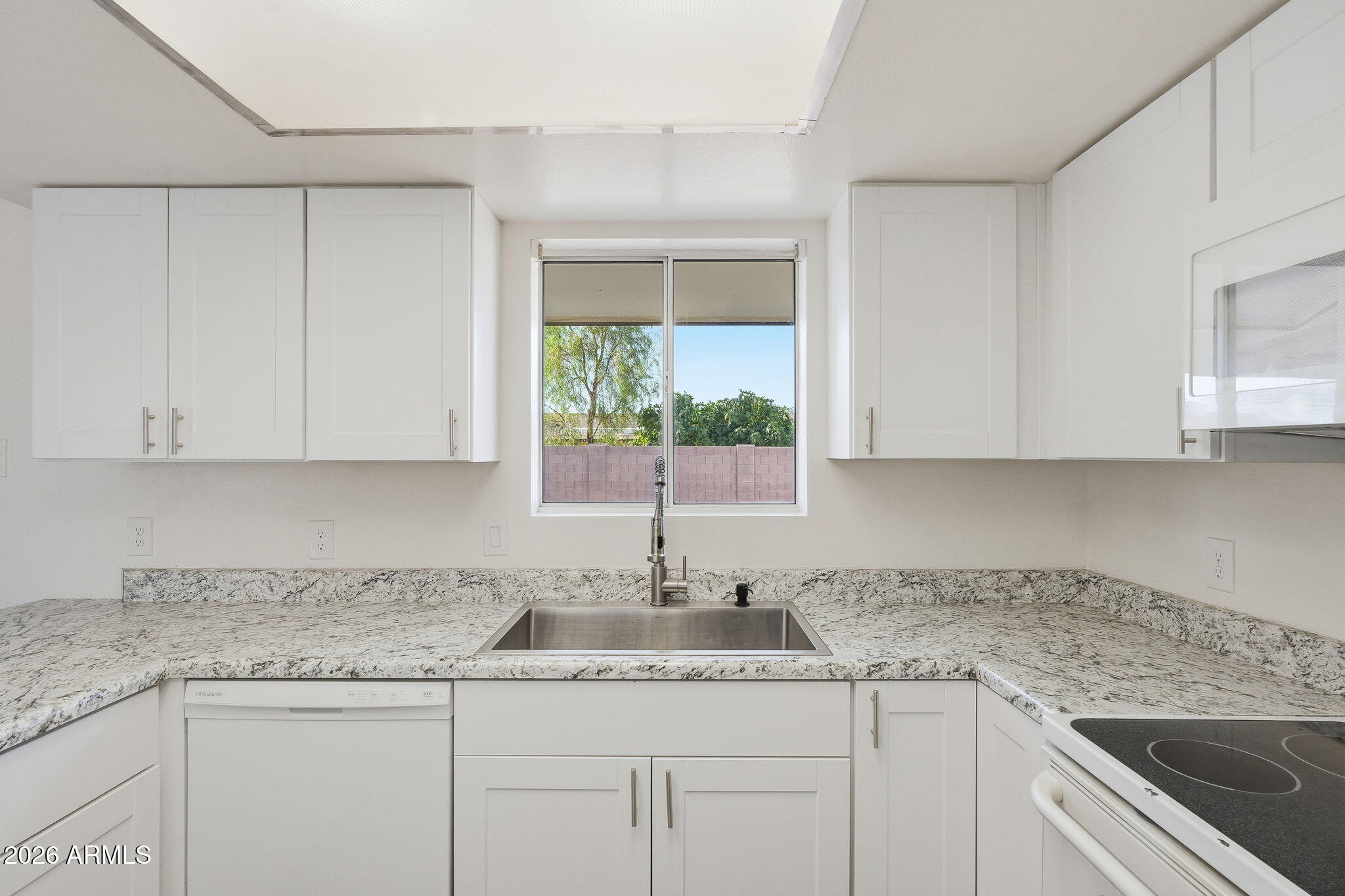 2302 East Nisbet Road Phoenix, AZ 85022 - Photo 4 of 22 a kitchen with granite countertop stainless steel appliances white cabinets sink and window